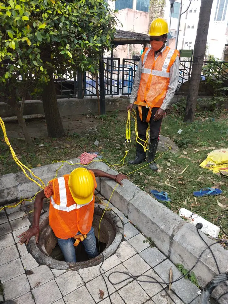 Technicians in safety helmets and hi-vis vests during confined-space tank entry