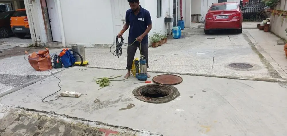Submersible pump and rope staged at a street-level manhole