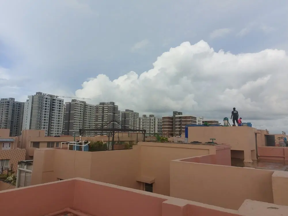 Wide view of rooftop water tank work with Kolkata high-rise skyline