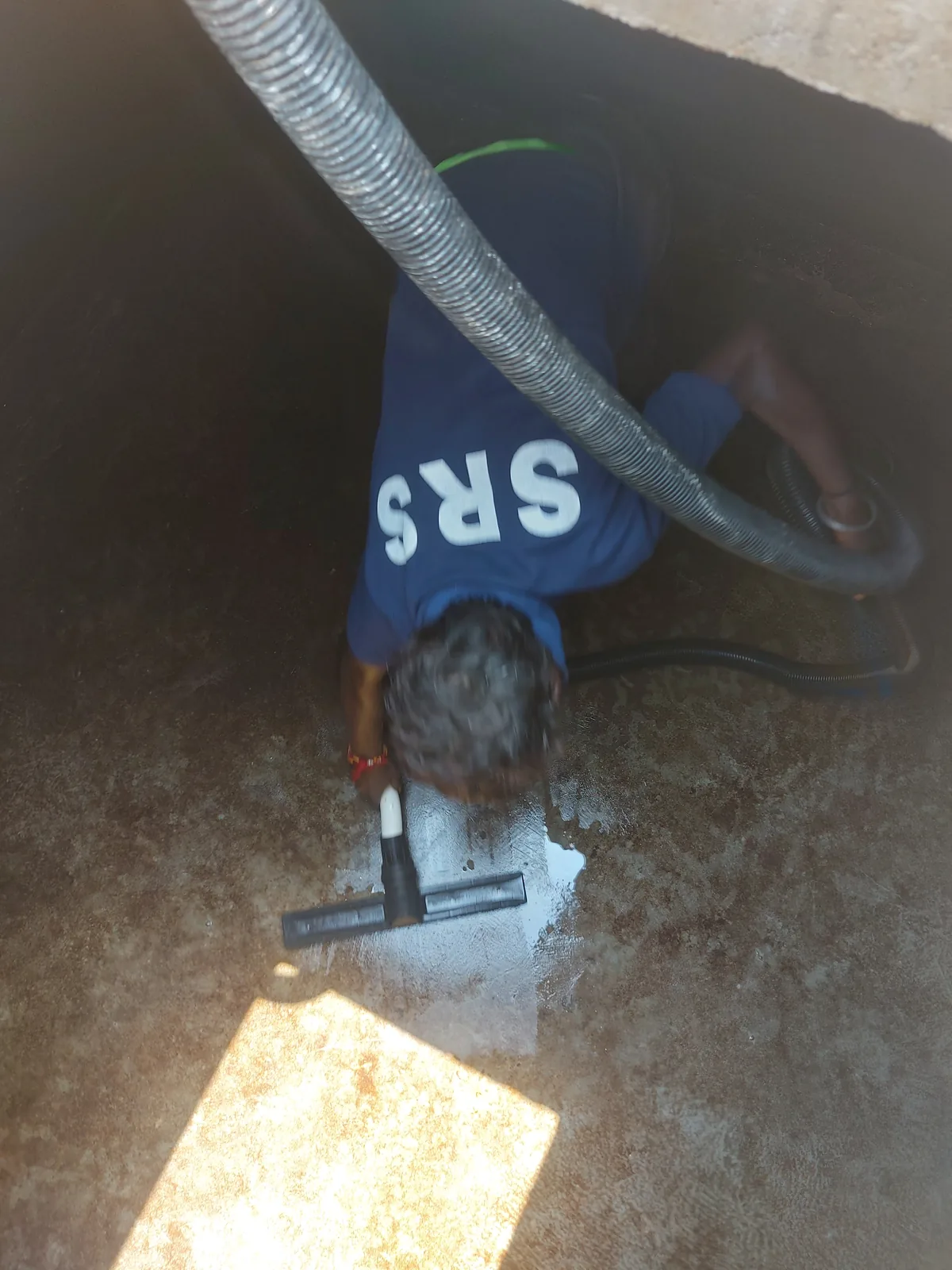 SRS technician vacuum cleaning the floor of a water tank